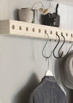 a coat rack with hats hanging from it's hooks and two coats on the hangers