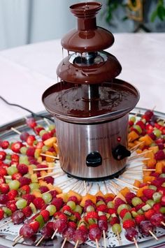 a chocolate fondant fountain with fruit on skewers and strawberries in the center