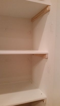 an empty white shelf in the corner of a room