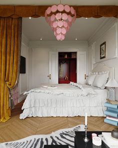 a bed room with a neatly made bed and a chandelier hanging from the ceiling