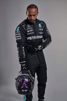 a man in a racing suit and helmet is looking down at his hand on his hip