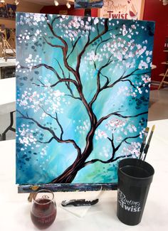 an acrylic painting of a tree with white flowers on it and a cup next to it