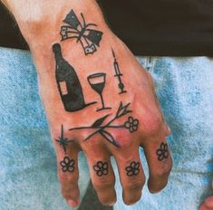 a person with a tattoo on their hand holding a wine glass and flower designs in front of them