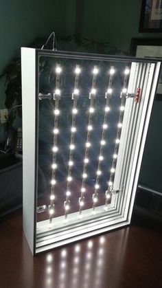 an open door with lights on it sitting on top of a wooden table next to a potted plant