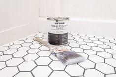 a paint can and brush sitting on a white tiled floor