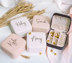 four small jewelry boxes sitting on top of a white table next to some gold beads