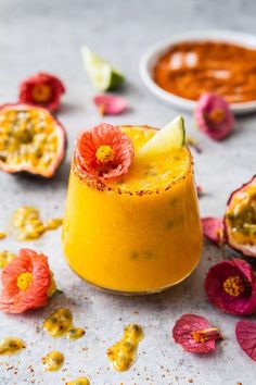 a small glass filled with liquid and garnished with flower petals on the table