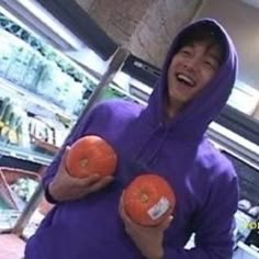 a man in a purple hoodie holding two oranges