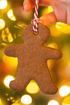 a hand holding a christmas ornament shaped like a gingerbread man with a candy cane