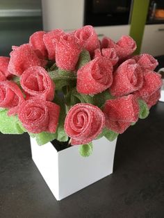 a white vase filled with pink roses on top of a table