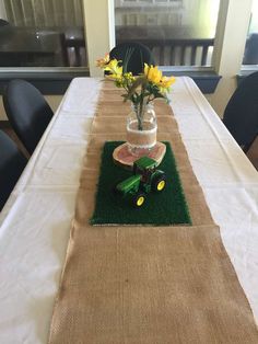 the table is set up with flowers in vases and green grass on the runner