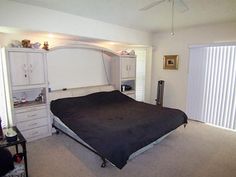 a bed room with a neatly made bed next to a sliding glass door and a window