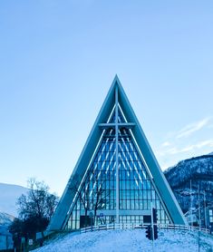 a large triangular shaped building sitting on top of a snow covered hill