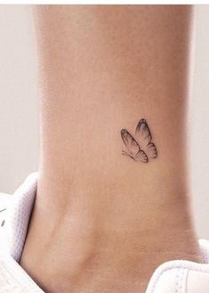 a small butterfly tattoo on the back of a woman's neck, with one wing flying