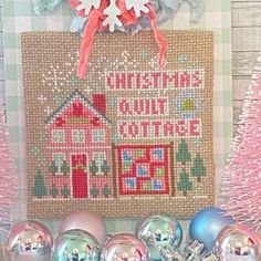 a cross stitch christmas ornament hanging on a wall next to ornaments and decorations