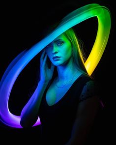 a woman is posing with her hands on her head and glowing neon lights behind her