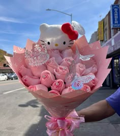 a hello kitty bouquet with pink roses in the foreground and a butterfly on top