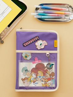 a pencil case sitting on top of a table next to markers and pen holders with cartoon characters