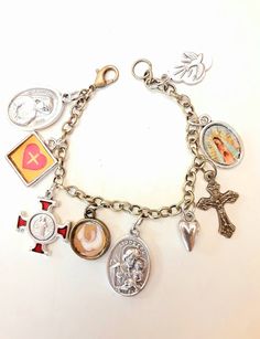 This is a fun and beautiful bracelet to help your devotional life and share the faith with others who see you wearing it. Great for Confirmation or that special mom. A beautiful gift for the Catholic lady on your list. Includes a St Benedict medal/cross, St Joseph medal, Holy Spirit Dove (made by me), Guadalupe charm (made by me), tiny heart, Holy Spirit medal, Jesus in my Heart charm (made by me), and a crucifix, all on a simple chain bracelet, brass tone base metal. Lobster clasp, choice of le St Benedict Cross, Holy Spirit Dove, Blessing Bracelet, St Benedict, Catholic Jewelry, Divine Mercy, Rosary Bracelet, Confirmation Gifts, Christian Jewelry