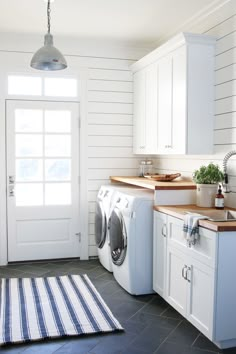 a washer and dryer in a white laundry room next to a kitchen counter