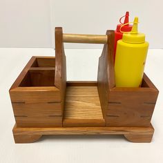 a wooden caddy with two cups and a mustard squeezer in it on a white surface