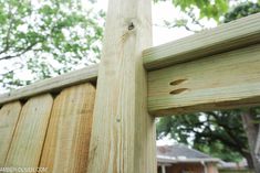 a wooden fence with holes in the top and bottom part, along with a house behind it