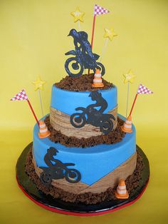 a three tiered cake is decorated with dirtbikes and stars on the top