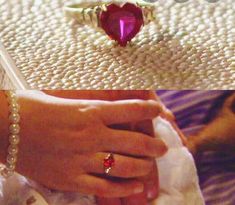 a woman's hand holding a cell phone with a heart shaped ring on it