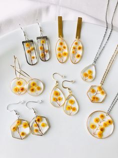 a white plate topped with different types of necklaces and earring sets covered in yellow flowers