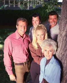 a group of people standing next to each other near a tree