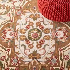 a red ottoman sitting on top of a rug next to a white and brown floor