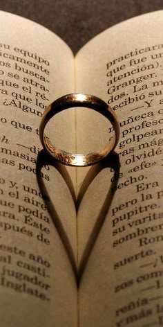 a heart shaped ring casts a shadow on an open book