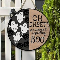 a wooden sign hanging from the side of a white fence with ghost decorations on it