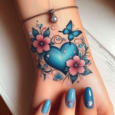 a woman's hand with blue and pink flowers, butterflies and heart tattoo on it