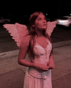 a woman with angel wings standing on the sidewalk