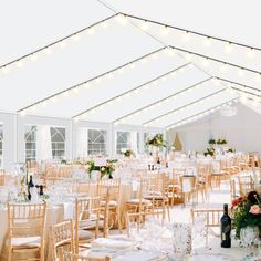 tables and chairs are set up in a tented area with string lights strung across the ceiling