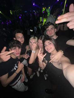 a group of young people posing for a photo at a party with their fingers in the air