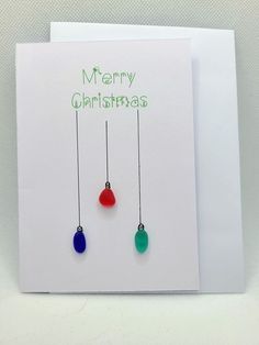 a christmas card with two dangling ornaments on the front, and merry christmas written on the back