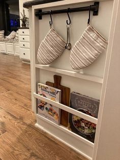 two pots and pans are hanging on the wall above a book shelf in a kitchen