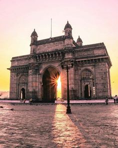 the sun shines brightly in front of an old stone building with arches and towers