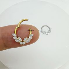 a gold nose ring with crystal leaves on it and an earring in the background