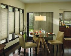 a dining room table and chairs with blinds on the windows behind them in front of a window