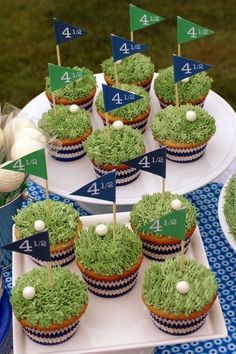 cupcakes decorated with green grass and white golf balls on a blue table cloth