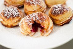 powdered sugar covered pastries on a white plate with raspberry fillings