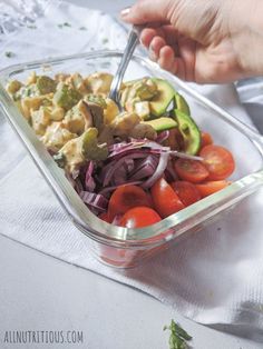 a person holding a fork over a salad in a plastic container