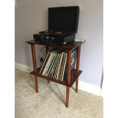 an old record player is sitting on top of a small table with records in it