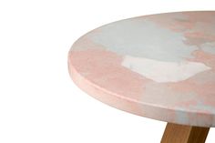 a pink and white marble table with wooden legs