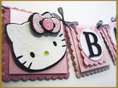 a hello kitty birthday banner hanging on a wall next to a white and pink background