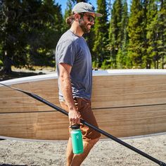 a man holding a surfboard and drinking water