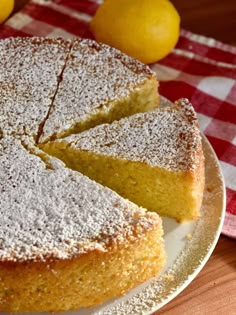 a cake on a plate with two slices taken out of it and some lemons in the background